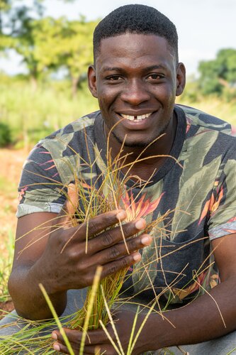 Hadid Adébola Gangni-Ahossou, a graduate student working with screening fonio accessions, shows fonio from his plots. Photo: Michael Major/Crop Trust