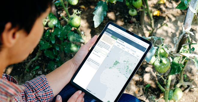man looking at an ipad screen that shows a map of seed accessions